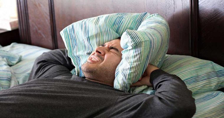 a man having trouble sleeping squeezes a pillow around his ears for some peace and quiet Ht0bpVdASo 760x400 1